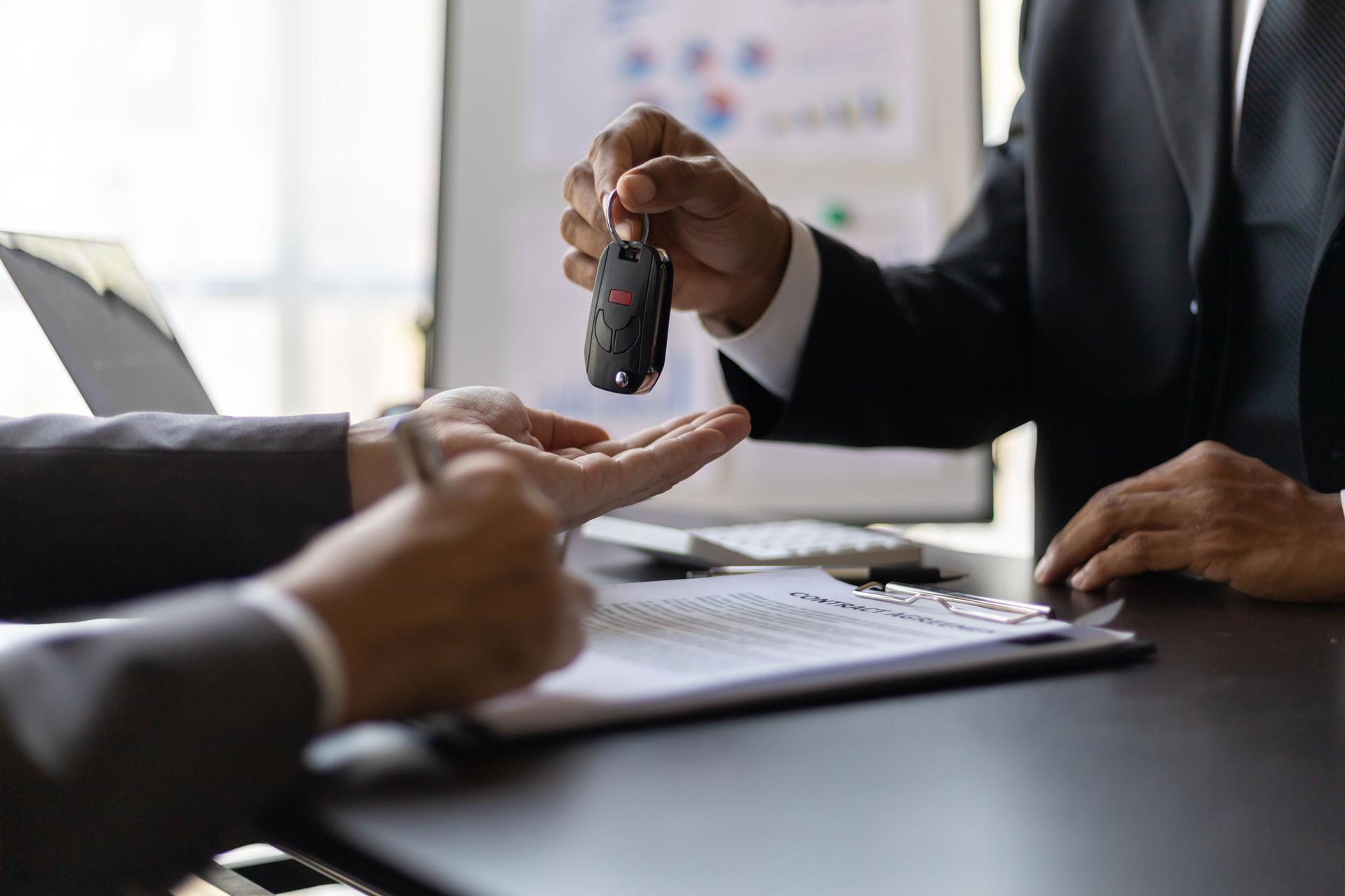 Customer signing car purchase or lease contract agreement with car salesman, car insurance.